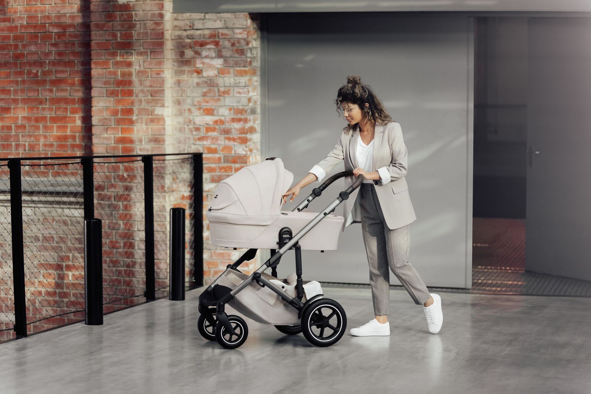 Elternteil schiebt einen SMILE 5Z Kinderwagen mit Babywanne und schaut sanft nach dem Baby.
